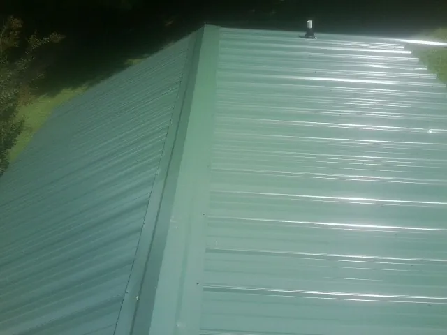 New green metal panels meeting at the ridge of a roof — Flat Roof Repair work by our crew in Dendron