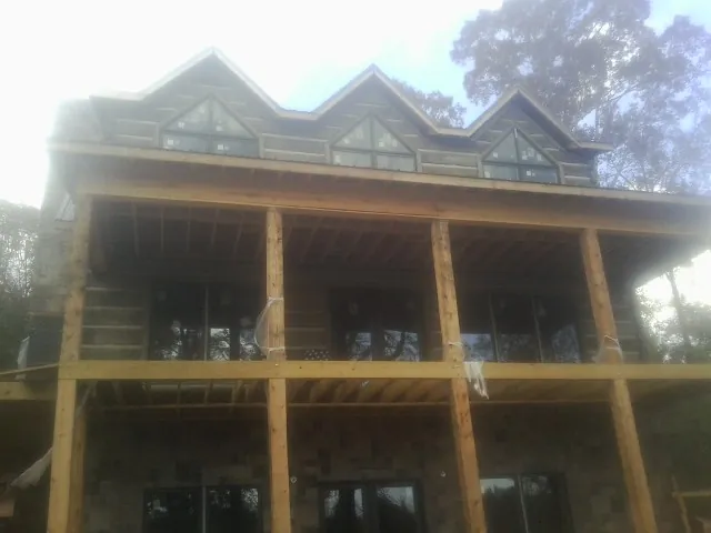 Dormers and porch framing on a large log home under construction — Roof Coating work by our crew in Dendron